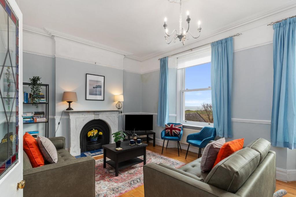 a living room with two couches and a fireplace at Penalun House - Beautiful Sea Views in Penally