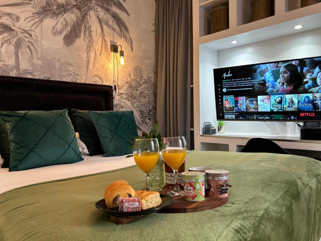 a tray of food and drinks on a bed with a tv at Appart'TERRASSE - 20mn STADE U ARENA - CHAMPS ÉLYSÉES - BEST PLACE JO 2024 in Maisons-Laffitte