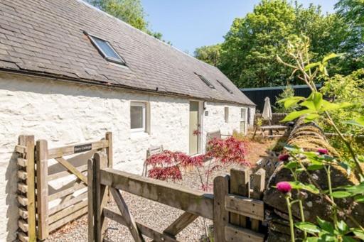 a white building with a wooden fence and a garden at Barn Cottage 2 bedroom with gorgeous views in Dunblane