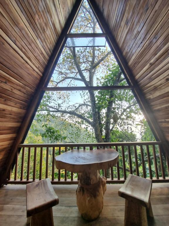 姆杜克的住宿－Munduk Umah Cabin，一张桌子和两张长椅,位于带大窗户的房间里