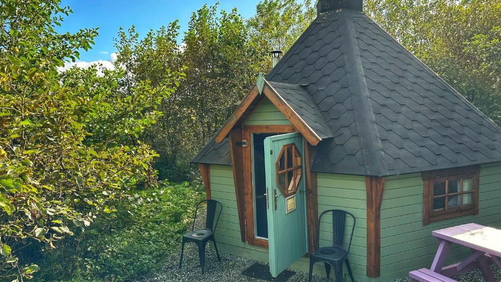 een kleine schuur met een dak en een tafel en stoelen bij Skye Eco Bells in Dunvegan