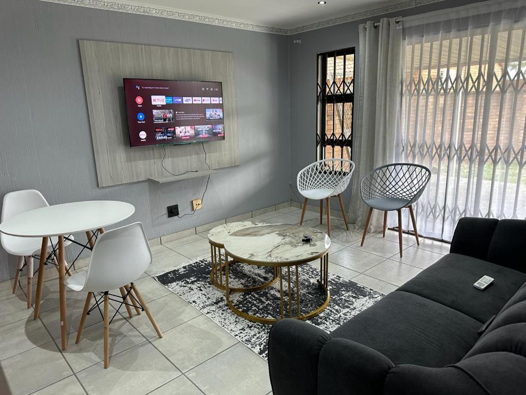 een woonkamer met een bank en tafels en stoelen bij Beautiful 2 bedroom apartment In Richard's bay in Richards Bay