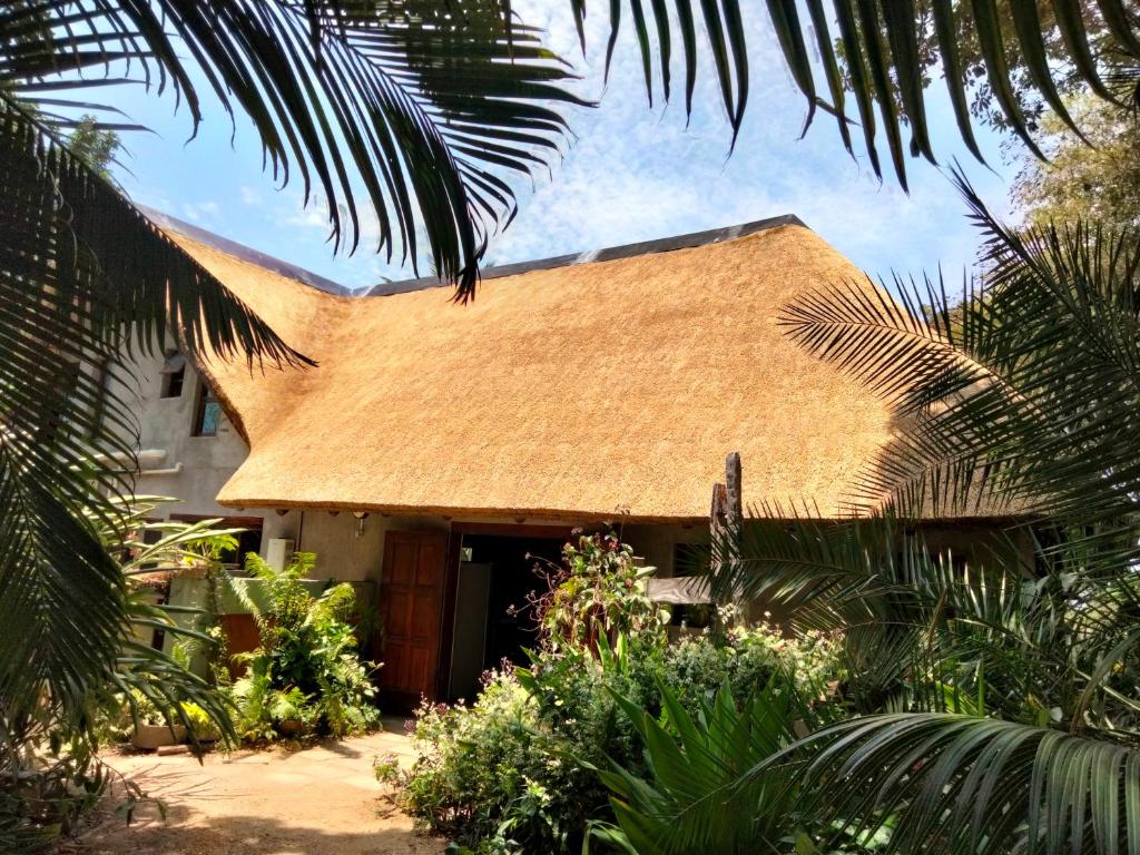 une maison avec un toit de chaume dans un jardin dans l'établissement Casa Jardim, à Vilanculos