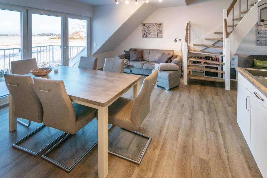 uma cozinha e sala de estar com uma mesa de madeira e cadeiras em Nordseenest em Neßmersiel