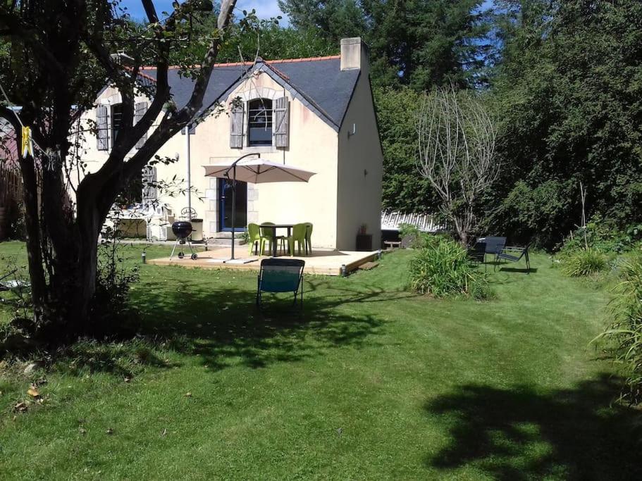 una casa bianca con tavolo e sedie in cortile di La maison au cœur de la forêt a Rosporden