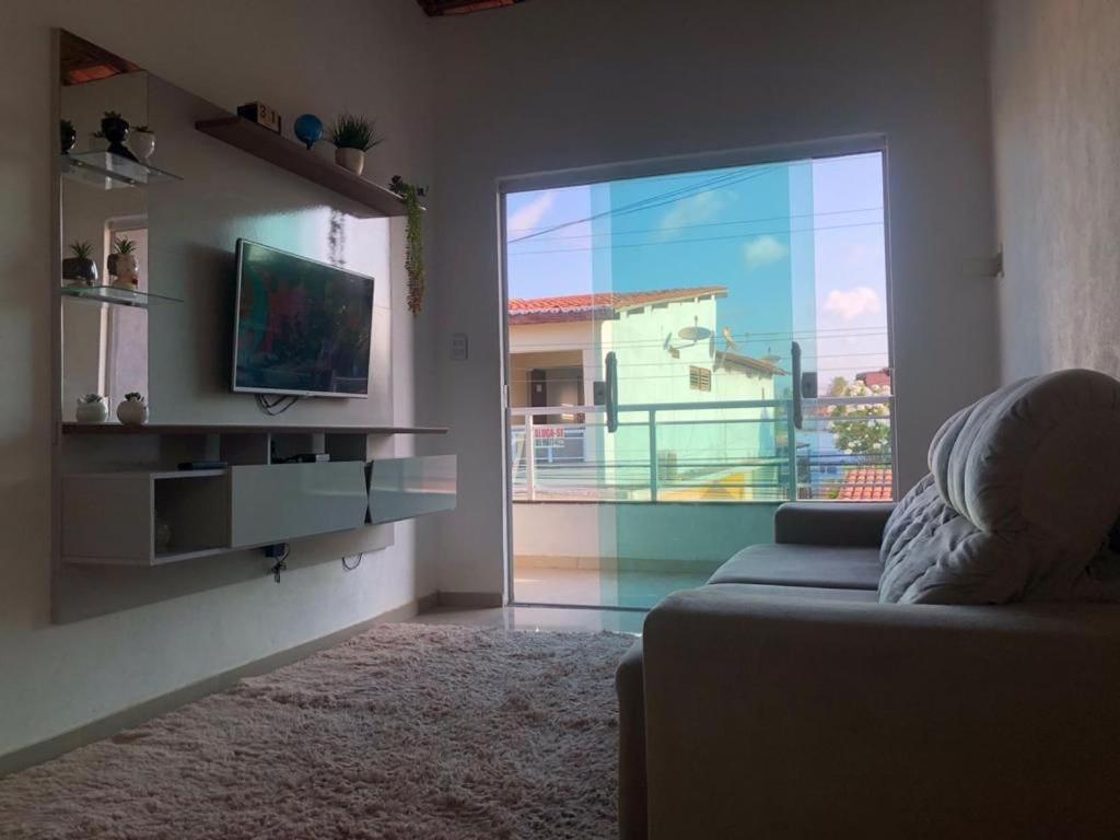 een woonkamer met een bank en een groot raam bij Casa e suítes da Vava in Trairi