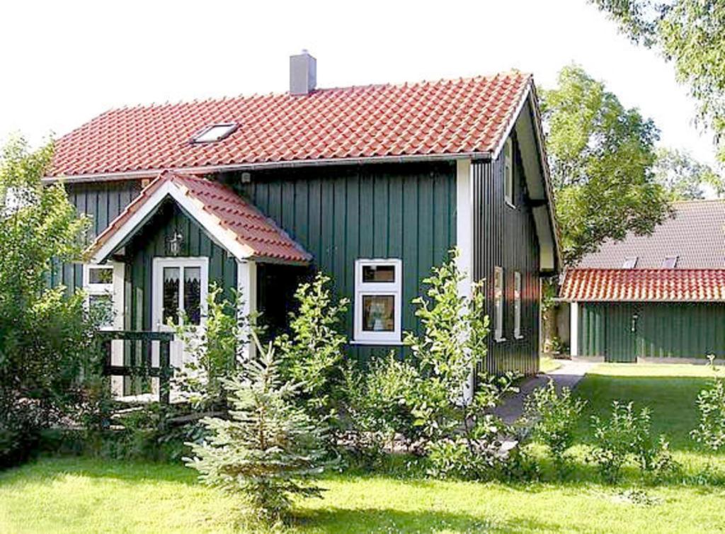 uma pequena casa verde com um telhado vermelho em Sommerhaus am Meer em Barsfleth