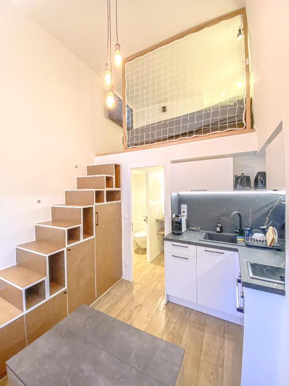 une cuisine avec des placards blancs et un escalier dans une pièce dans l'établissement Charmant Studio Cosy Central, à Manosque