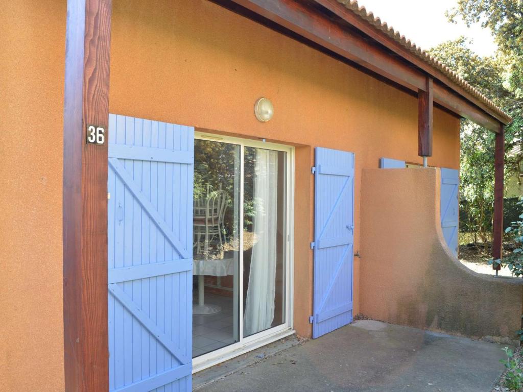 uma garagem com portas azuis ao lado de uma casa em Maison Narbonne, 3 pièces, 5 personnes - FR-1-229B-94 em Narbona
