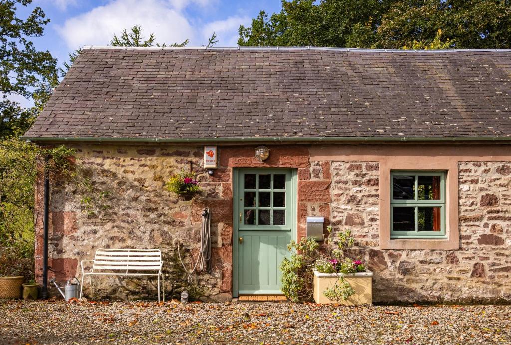 a stone cottage with a green door and a bench at Stable Cottage, Gartocharn, Loch Lomond in Alexandria