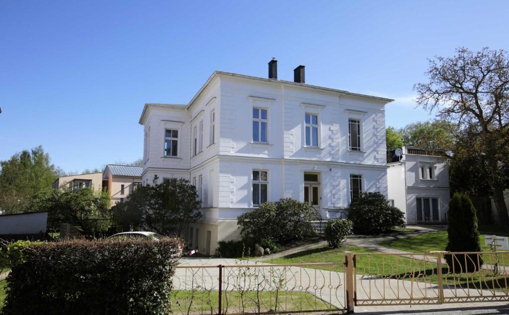 ein weißes Haus mit einem Zaun davor in der Unterkunft Villa Ruthenberg in Heringsdorf