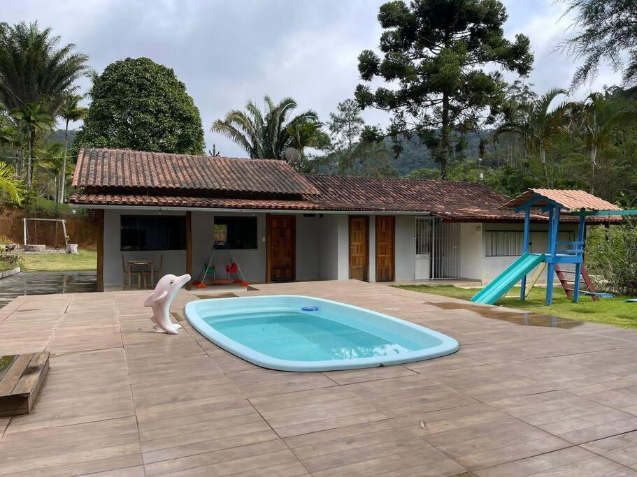 a swimming pool in front of a house with a playground at Chácara em Marechal Floriano in Marechal Floriano