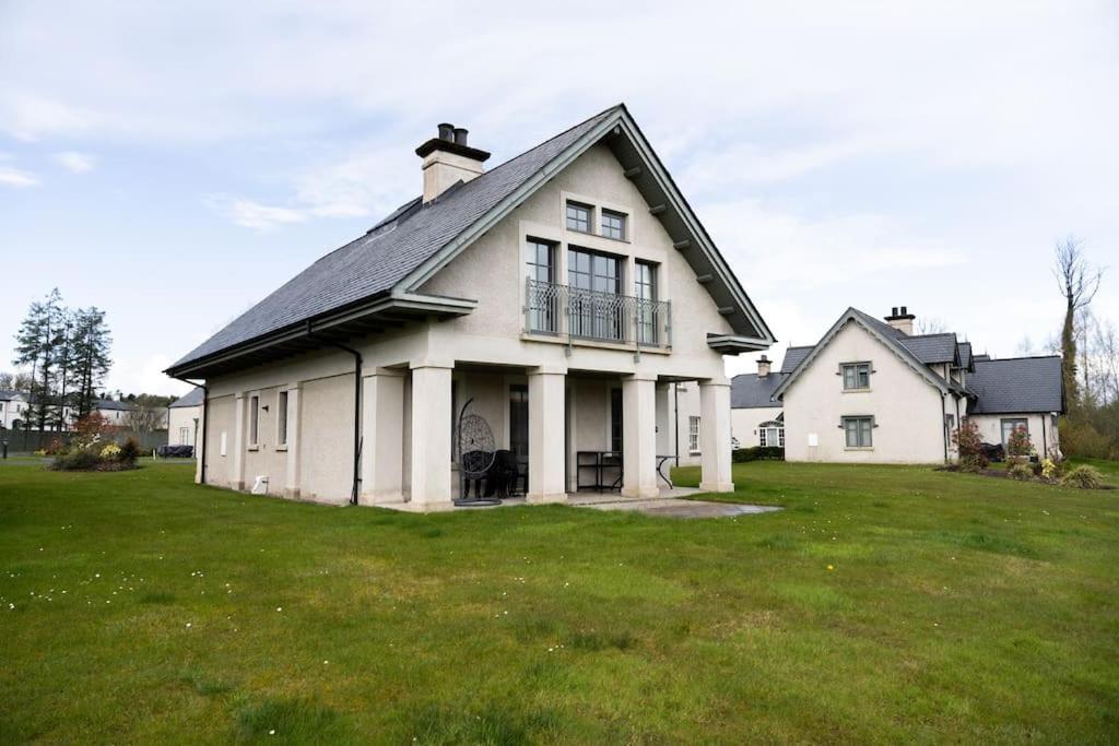 a large white house on a grass field at Luxury Lodge-Lough Erne Resort in Ballycassidy