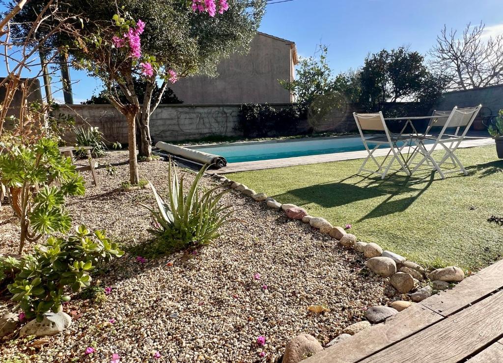 un jardin avec deux chaises et une piscine dans l'établissement Appartement l'Arancetu vue mer avec piscine, à Biguglia