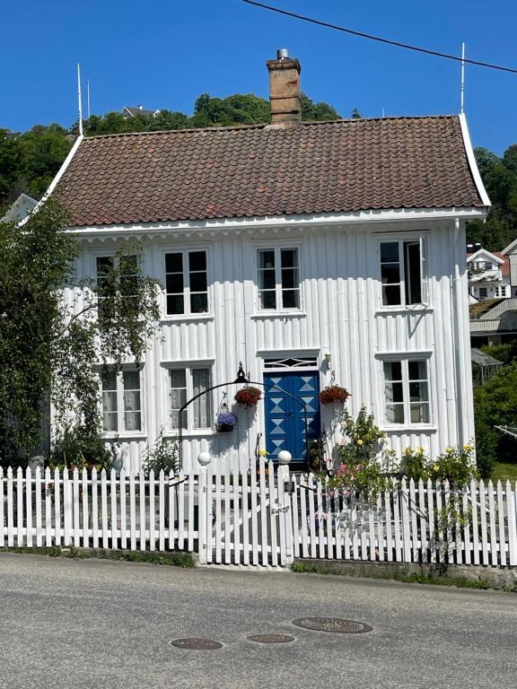 una casa blanca con una valla blanca y una puerta azul en Sommerdrøm i sør, en Mandal