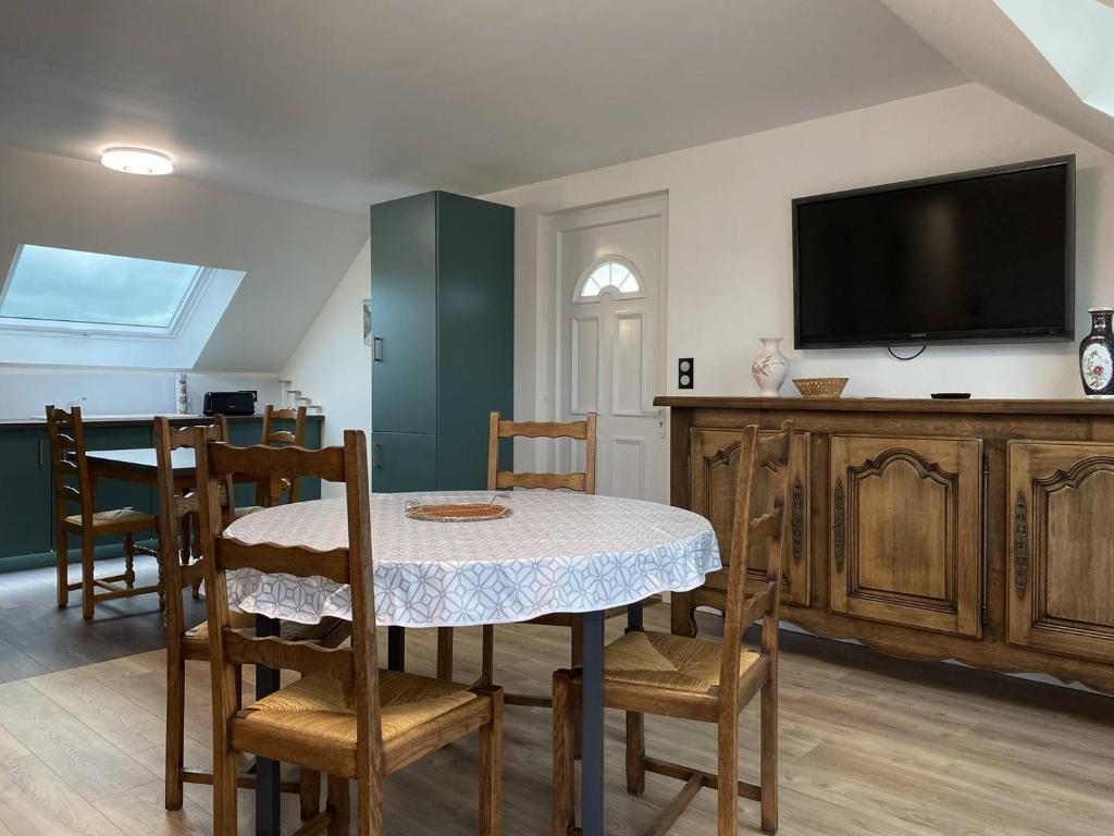 a dining room with a table and chairs and a tv at 211 - T3 entièrement rénové en plein centre de Plurien à moins de 5 minutes des Plages in Plurien