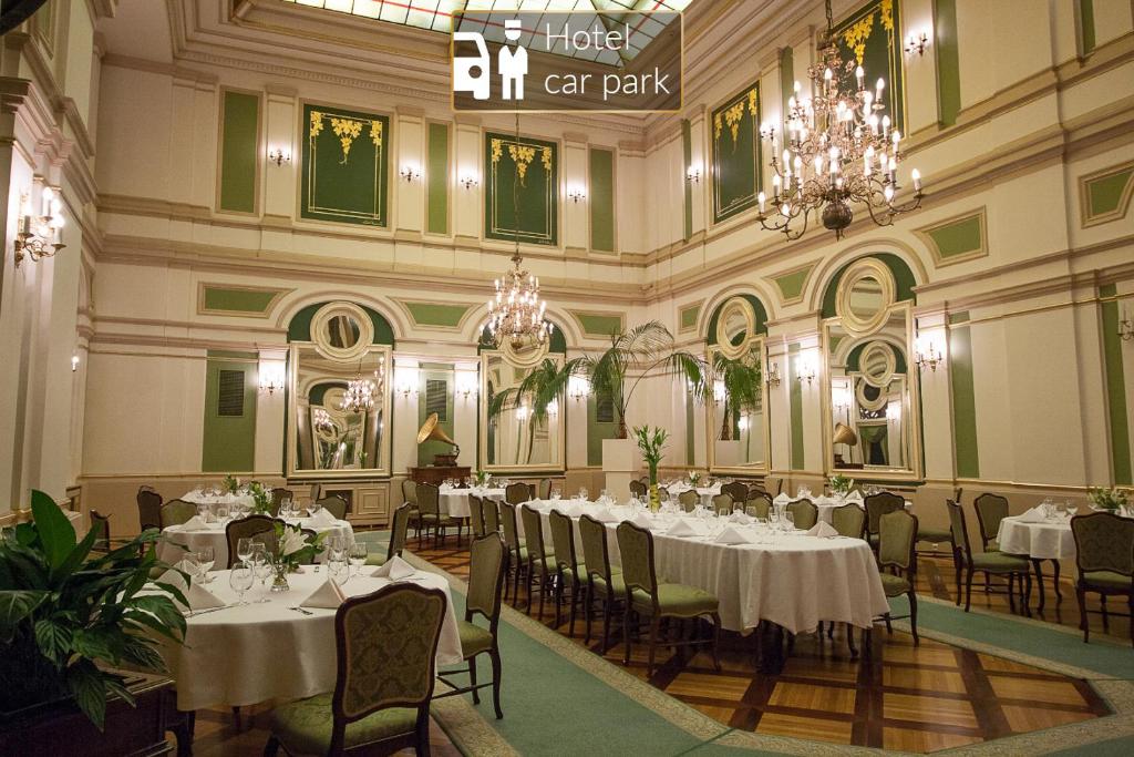 um salão de banquetes com mesas e cadeiras brancas e um lustre em Grand Hotel em Cracóvia