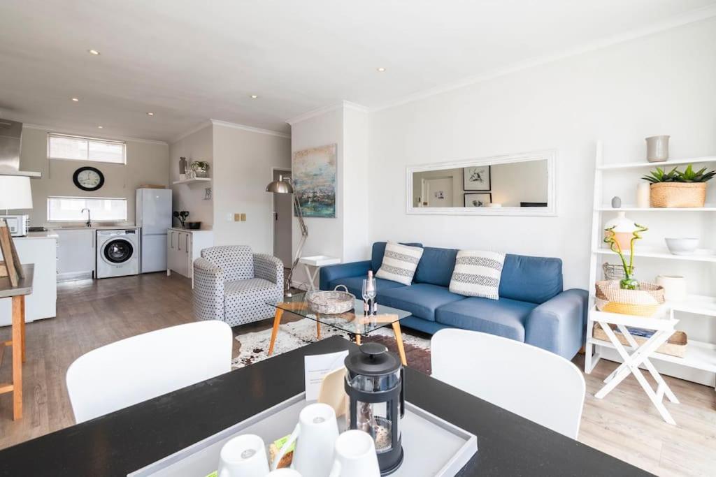 a living room with a blue couch and white chairs at Green Point Living with Stadium View in Cape Town