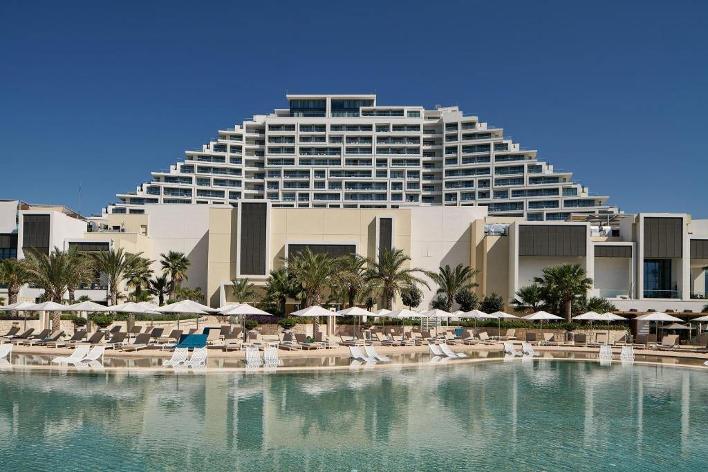 a resort with a pool and chairs and a building at City of Dreams Mediterranean - Integrated Resort, Casino & Entertainment in Limassol