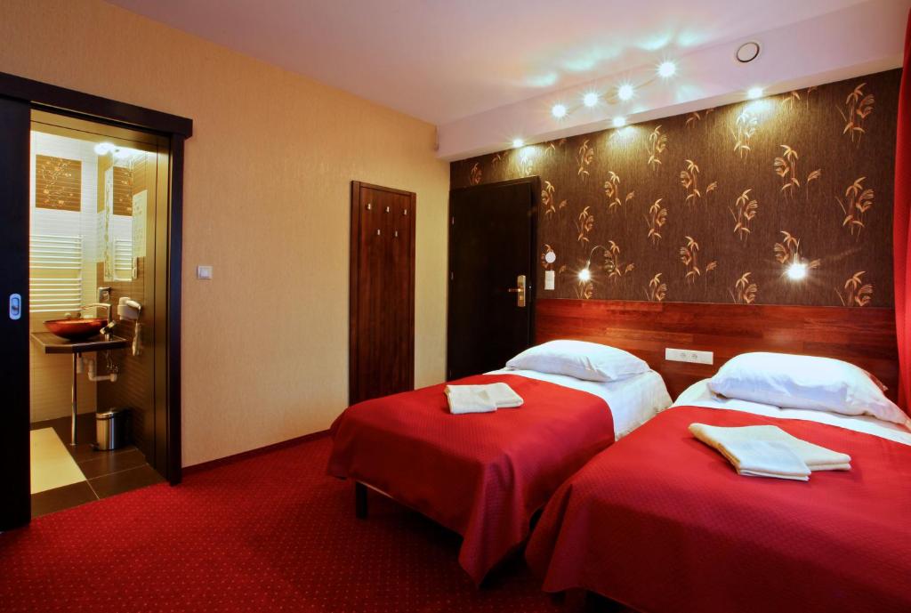 Habitación de hotel con 2 camas con sábanas rojas en Willa Magnolia, en Gdynia