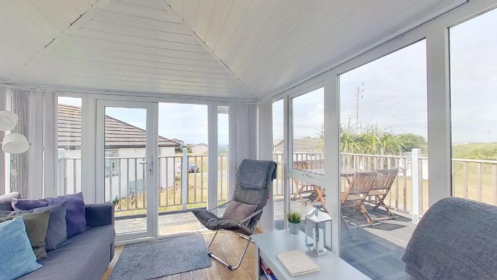 - un salon avec un canapé et des chaises sur une terrasse couverte dans l'établissement G23 Norda, Riviere Towans, à Hayle
