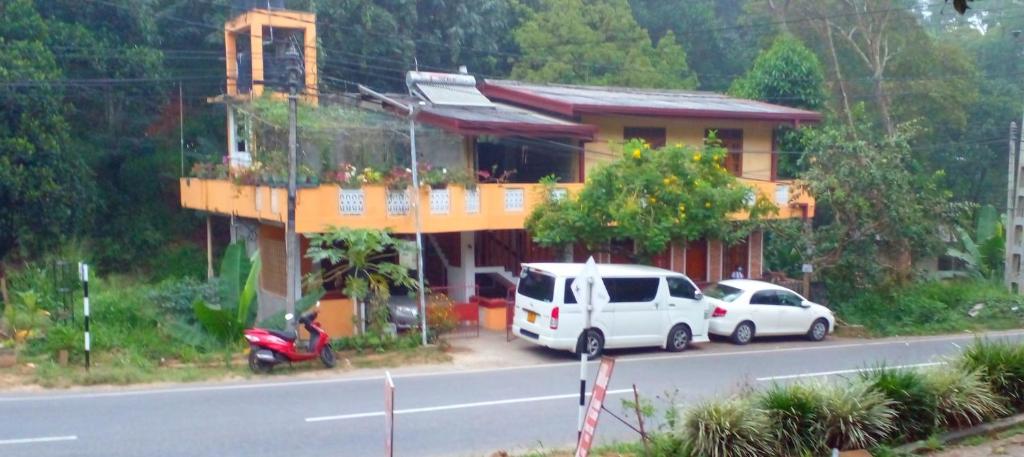 two cars parked in front of a house on the side of the road at Silent Night Homestay in Ella