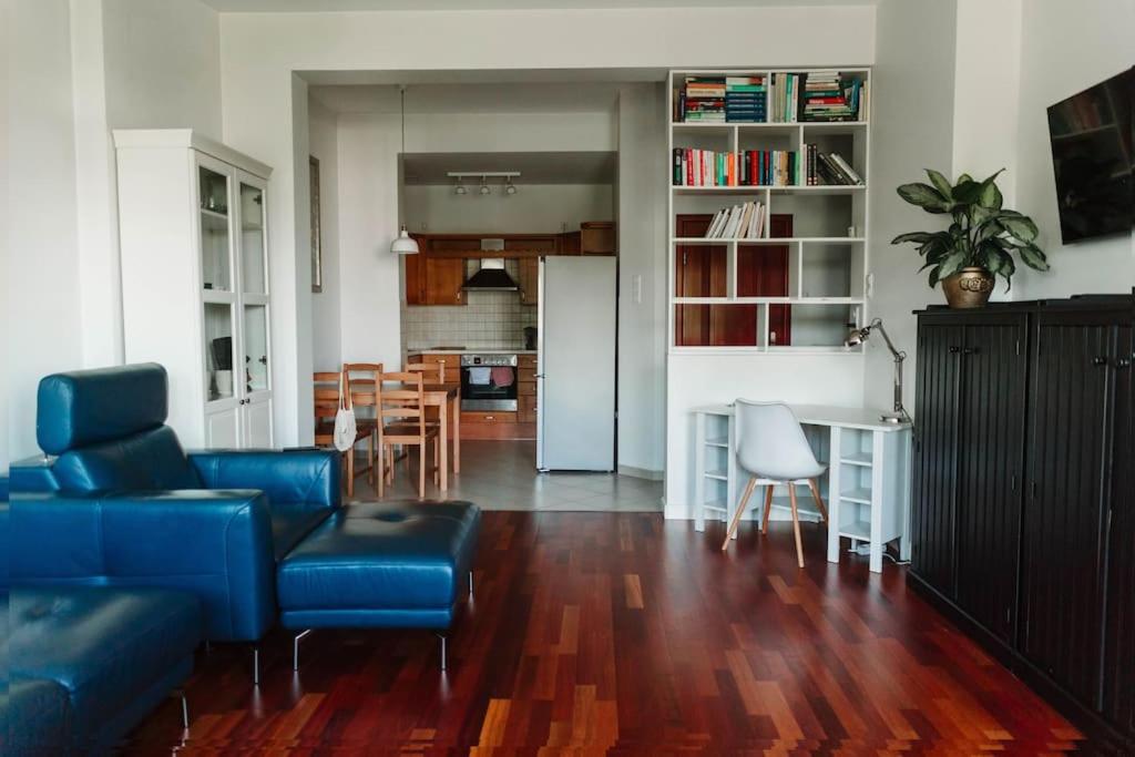 uma sala de estar com um sofá azul e uma cozinha em Apartament Planty 16C em Kielce