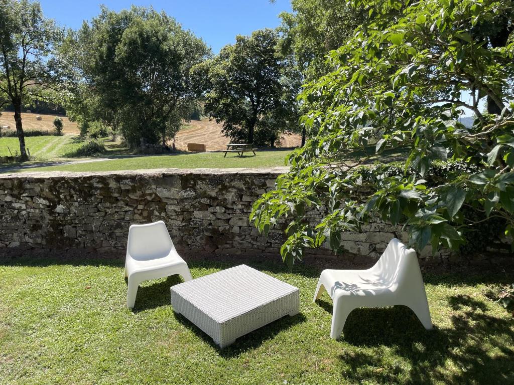 two white chairs and a bench in the grass at La maison Léopoldine 