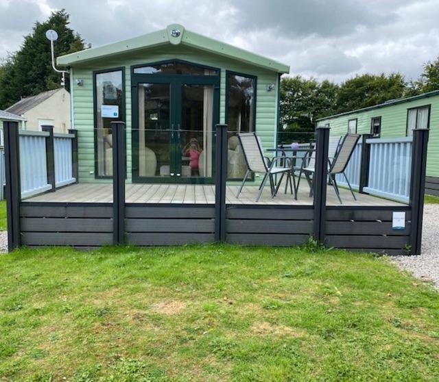 a house with a deck with a table and chairs at 28 Borwick Lakes in Carnforth