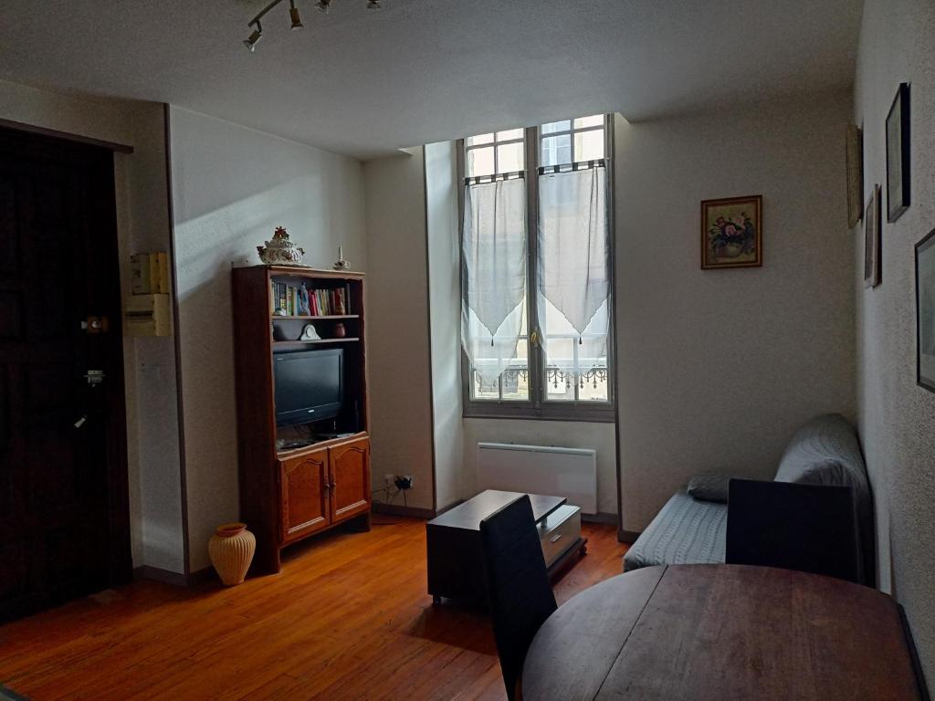 a living room with a table and a tv and a window at Appartement centre in Aire-sur-lʼAdour