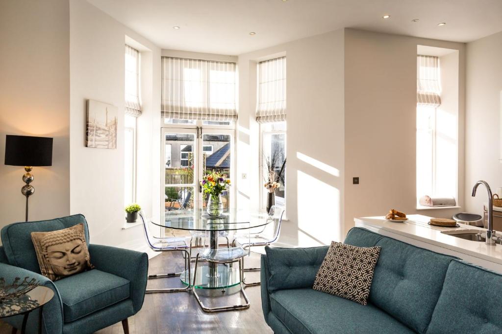 a living room with two blue chairs and a glass table at Gresham House in Eastbourne