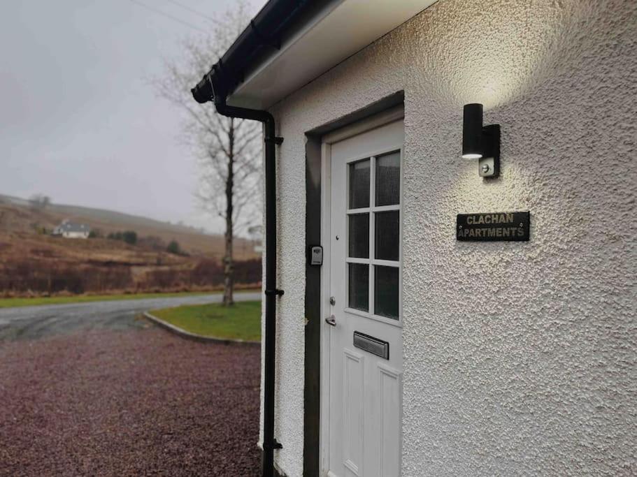 a white door on a building with a sign on it at One Bedroom Apartment - Carbost - Skye in Carbost