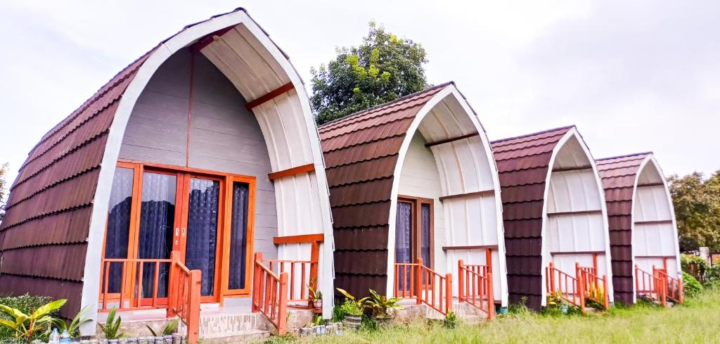 a group of three houses with orange doors at Tangga Bungalows in Sembalun Lawang