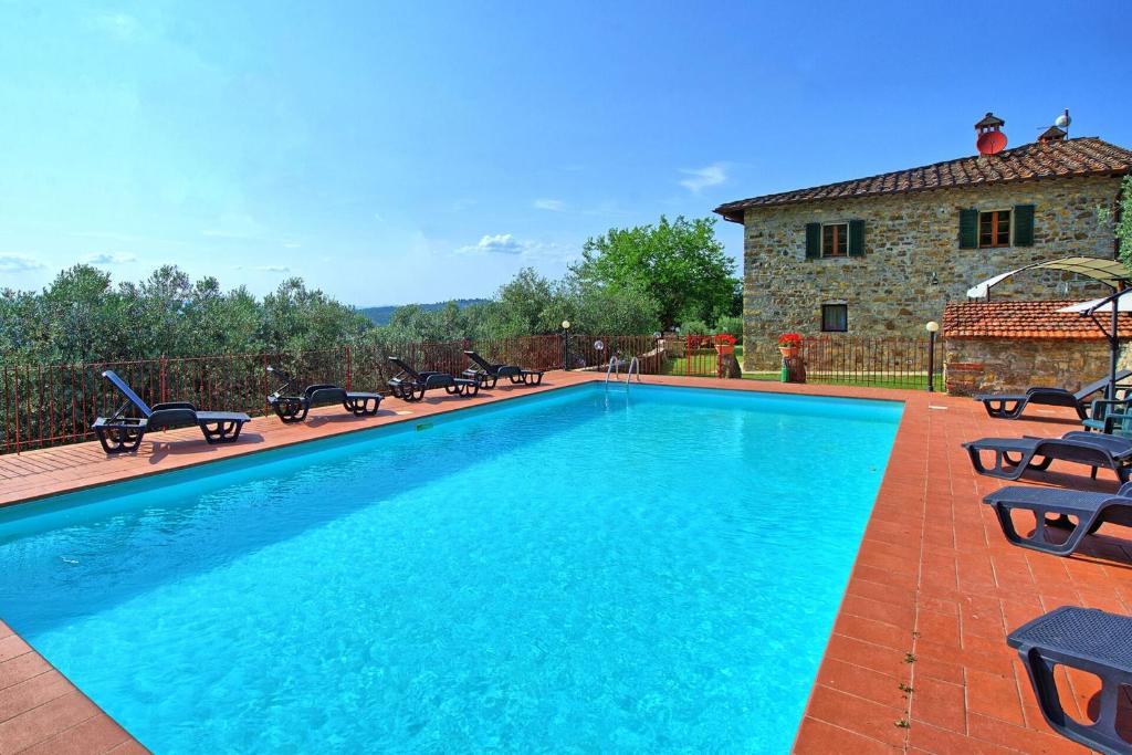 a large swimming pool with chairs and a house at Villa Quercina in Pieve a Presciano