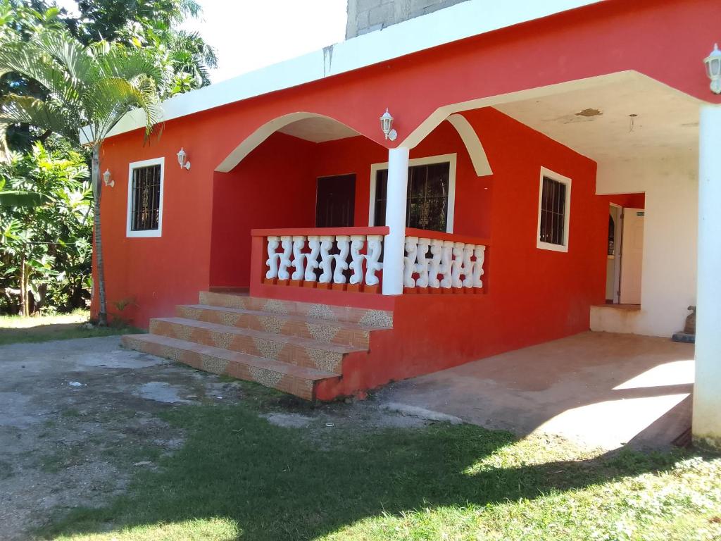 una casa roja con escaleras delante en Típica casa dominicana a 12 minutos de la playa, en Las Galeras