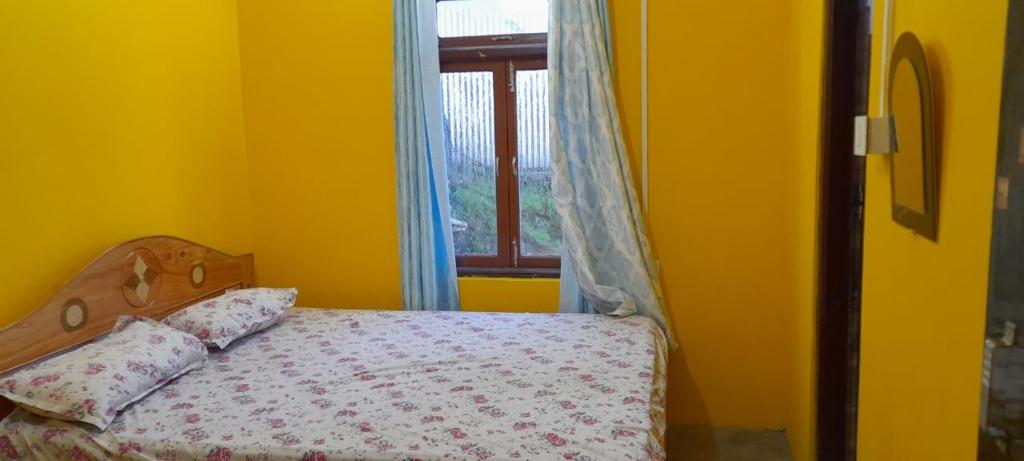 uma cama num quarto amarelo com uma janela em Teesta Stay & Restaurant em Darjeeling