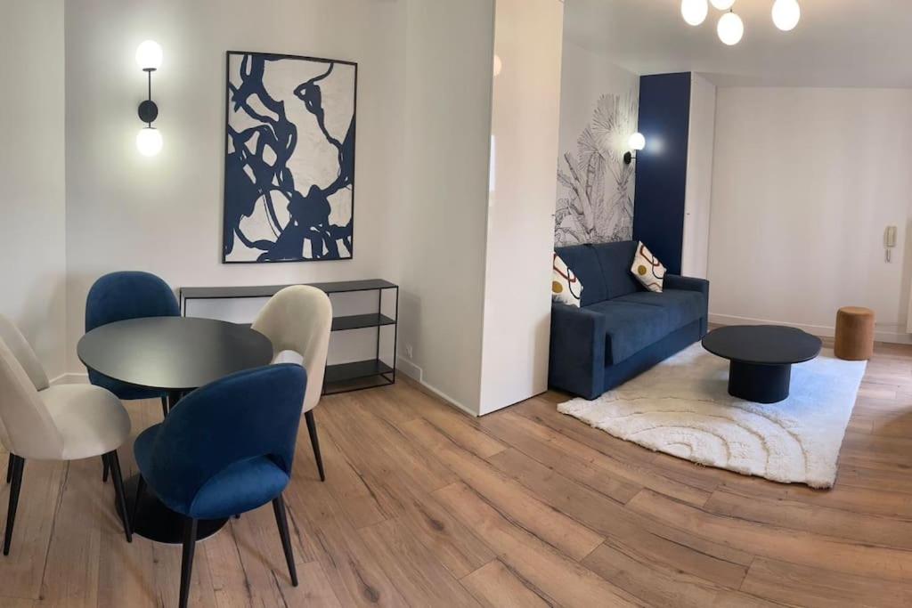sala de estar con sofá azul, mesa y sillas en Charmant studio cosy centre-ville - RUE4 en Rueil-Malmaison