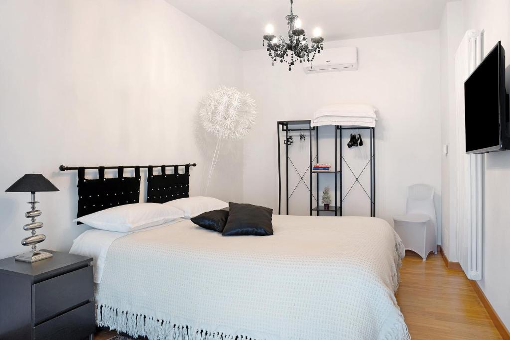 a white bedroom with a bed and a chandelier at Casa Gallinotto in Alba