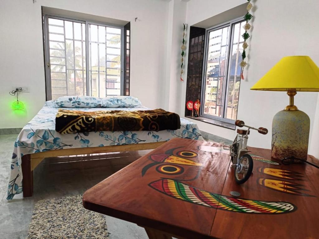 1 dormitorio con 1 cama y 1 mesa con lámpara en Traveller's Nest en Siliguri