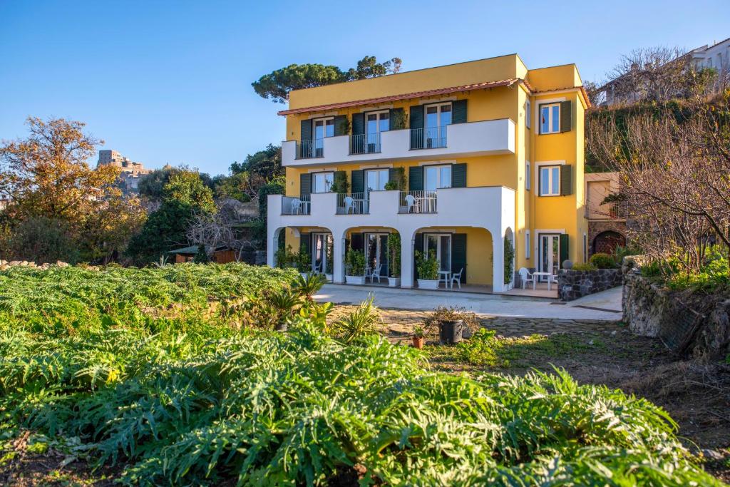 um edifício amarelo e branco com um quintal em B&B La Vigna Rooms - Ischia Ponte em Ischia