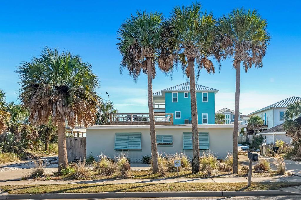 een huis met palmbomen ervoor bij Aquaverde Beach House in Pensacola Beach