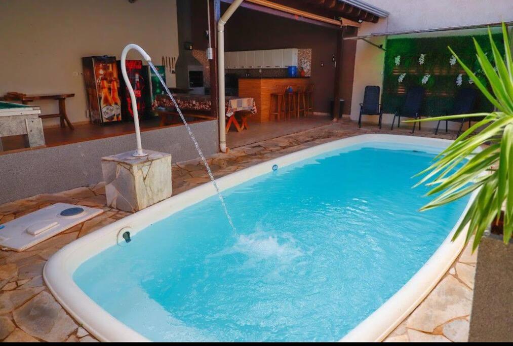 een groot zwembad met waterslang bij Rubi casa de temporada com piscina aquecida e área gourmet in Santa Fé do Sul