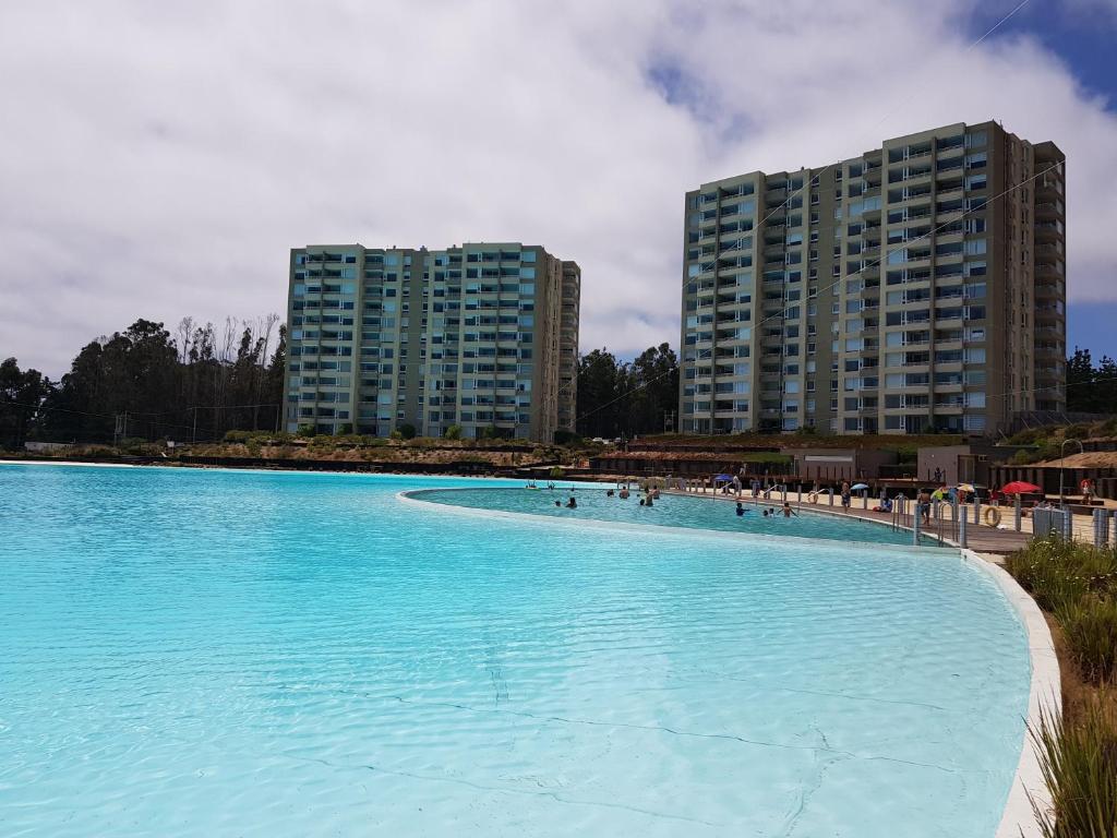 une grande piscine d'eau bleue devant de grands bâtiments dans l'établissement Depto con piscina y laguna artificial en Las cruces, à Las Cruces