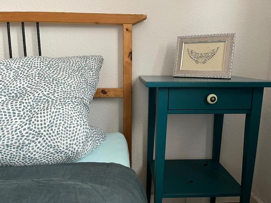 a blue nightstand next to a bed with a picture on it at Gemütlichkeit mit Cityblick in Leipzig