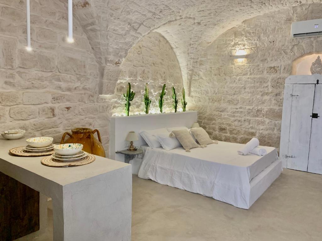 a white bedroom with a bed and a table at Dimore i Messapi Suites in Ceglie Messapica
