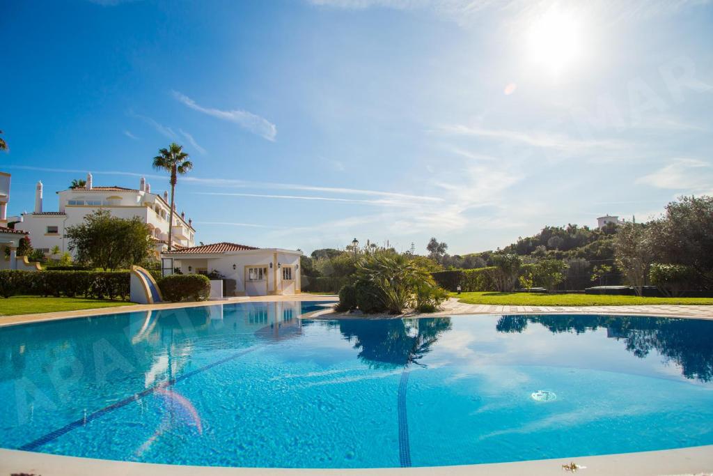 una grande piscina con acqua blu di fronte a una casa di Vila Golfemar a Poço Partido