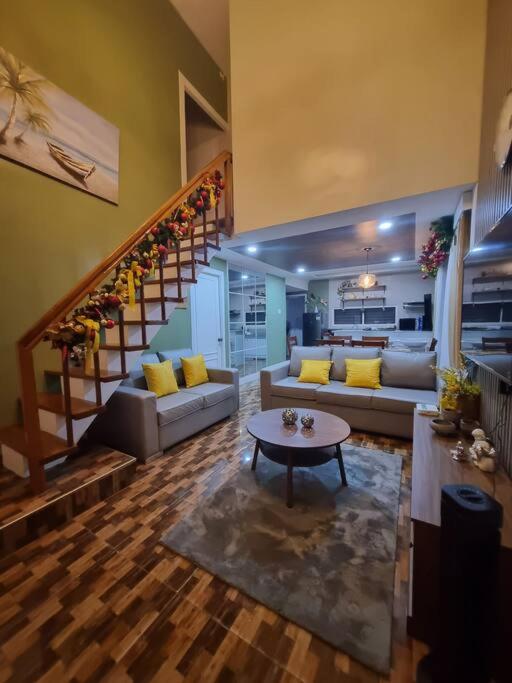 ein Wohnzimmer mit einer Treppe und gelben Kissen in der Unterkunft QHouse - 2 Storey House with 4 Bedrooms and 2 Bathrooms in Cagayan de Oro
