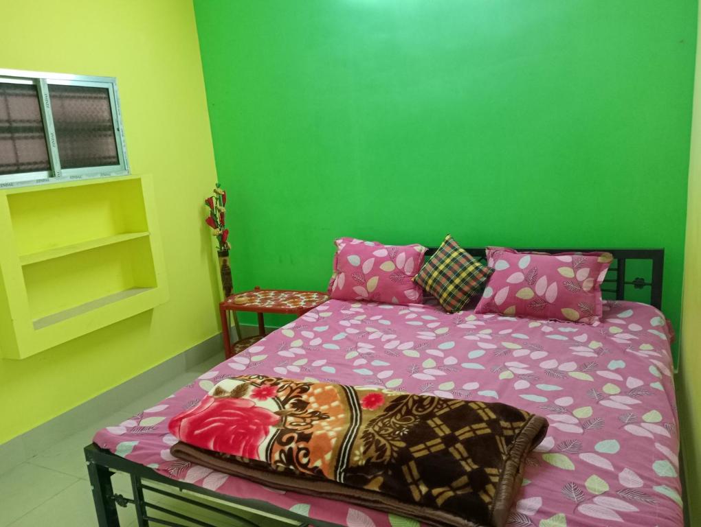 a bedroom with a bed and a green wall at SHALBITHI HOMESTAy in Bolpur