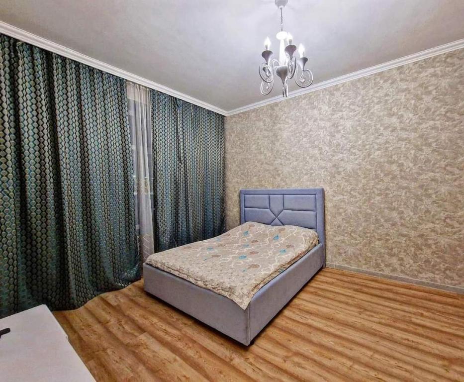 a bedroom with a bed and a chandelier at ЖК Чемпион in Taldykolʼ