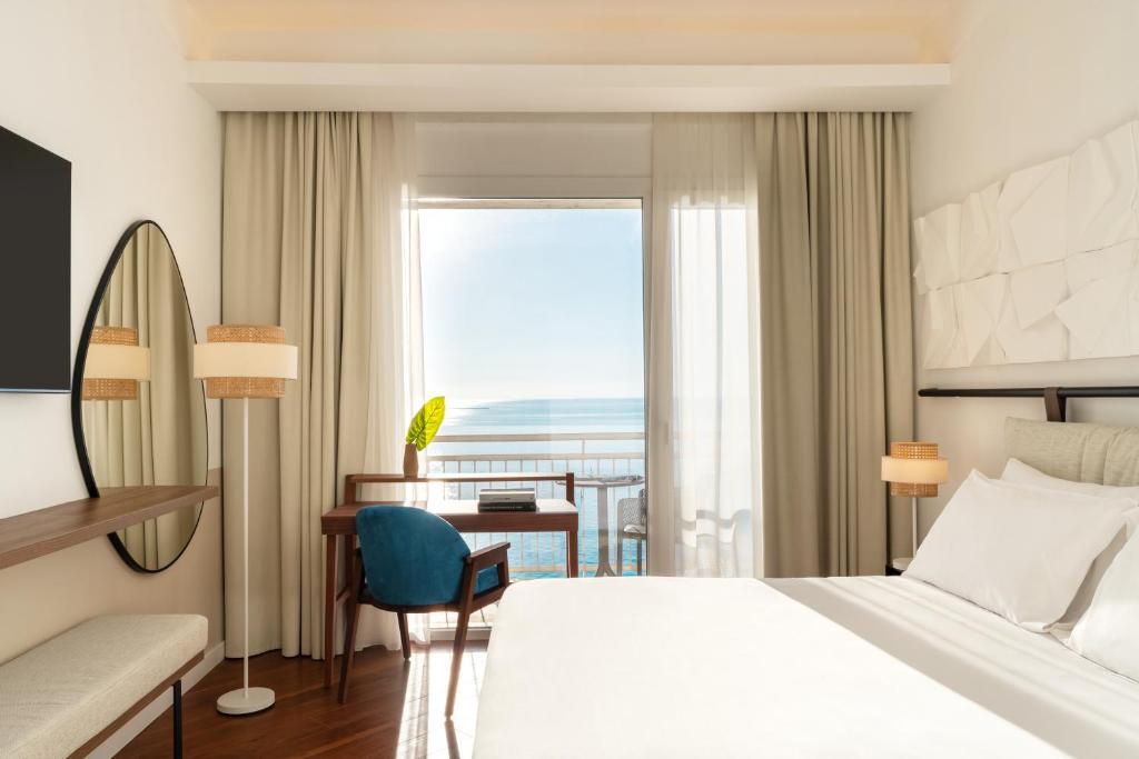 una camera d'albergo con letto, scrivania e finestra di Hotel Delfino Taranto a Taranto